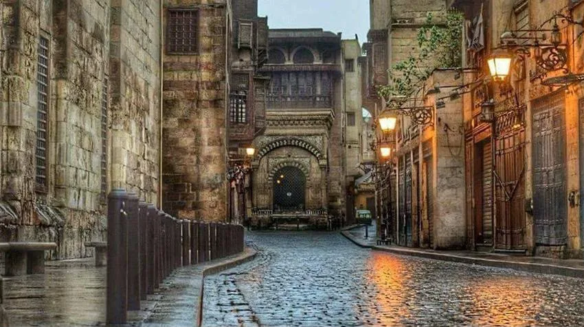 A stone-paved lane of Islamic Cairo glowing with lanterns at night