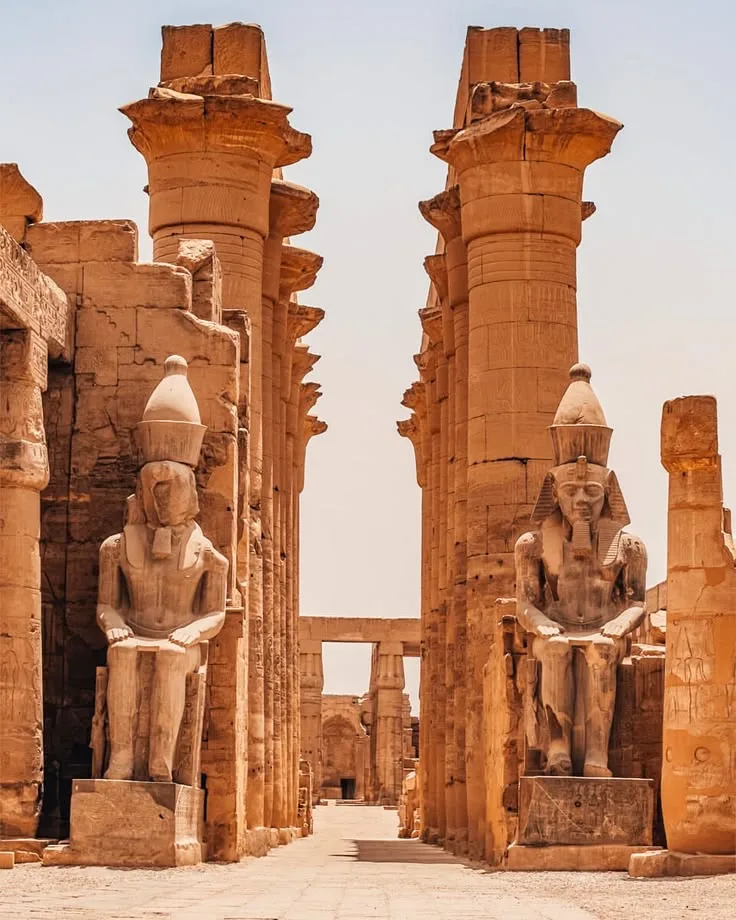 The colonnade of Luxor Temple with its seated royal statues, floodlit in the evening